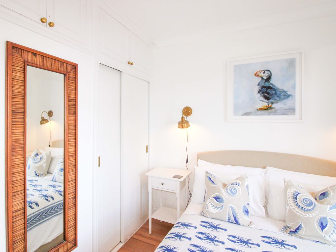A bedroom with a bed and a mirror at 4 The Elms in Salcombe