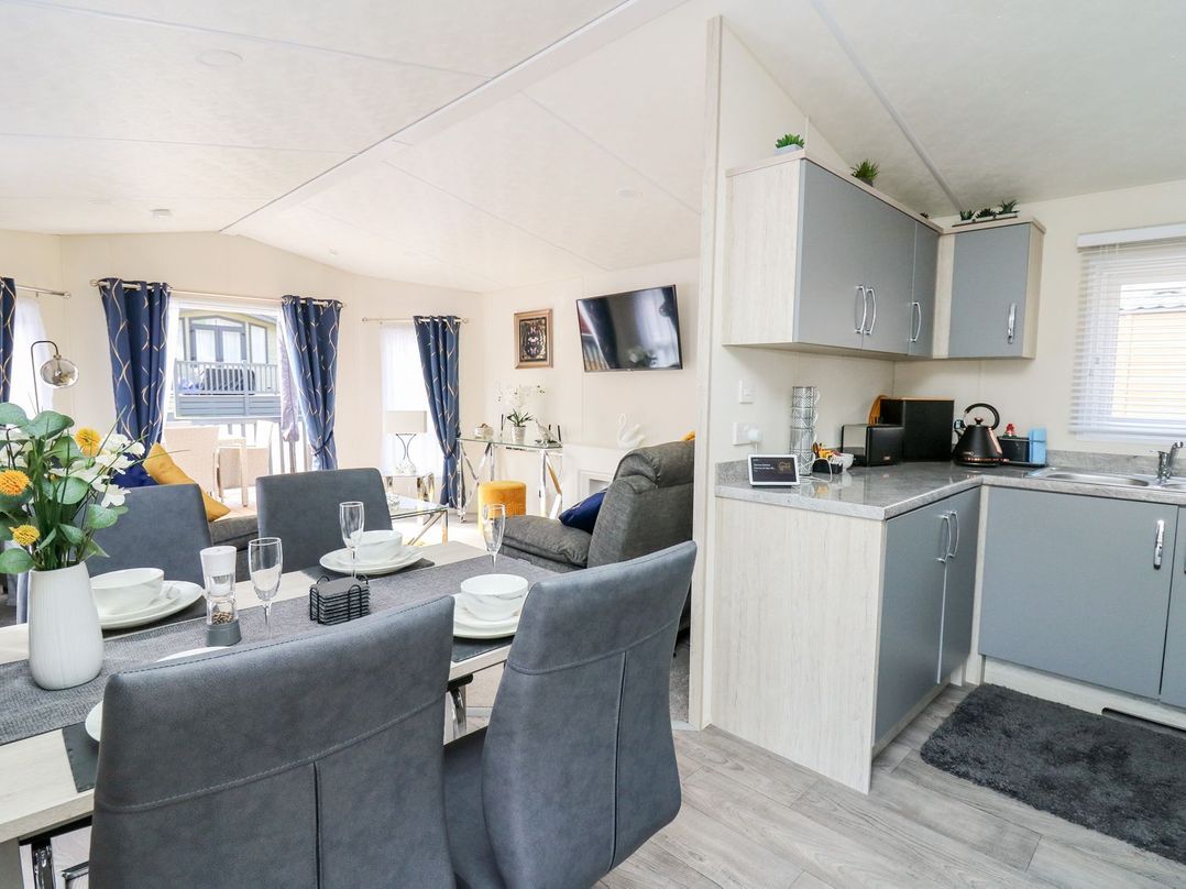 An open plan dining and kitchen area with table and chairs at 33 Woodpecker Lodge in Llanarth
