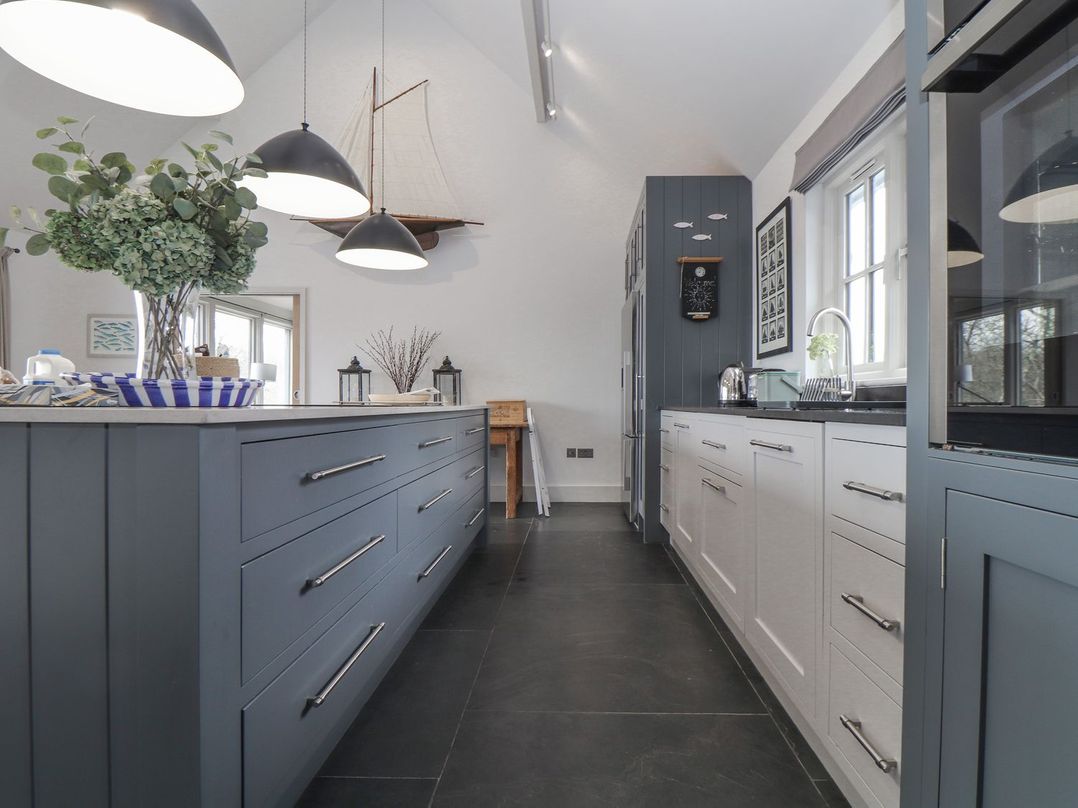 A kitchen with a central island and cabinets at Wood Meadow in Helston