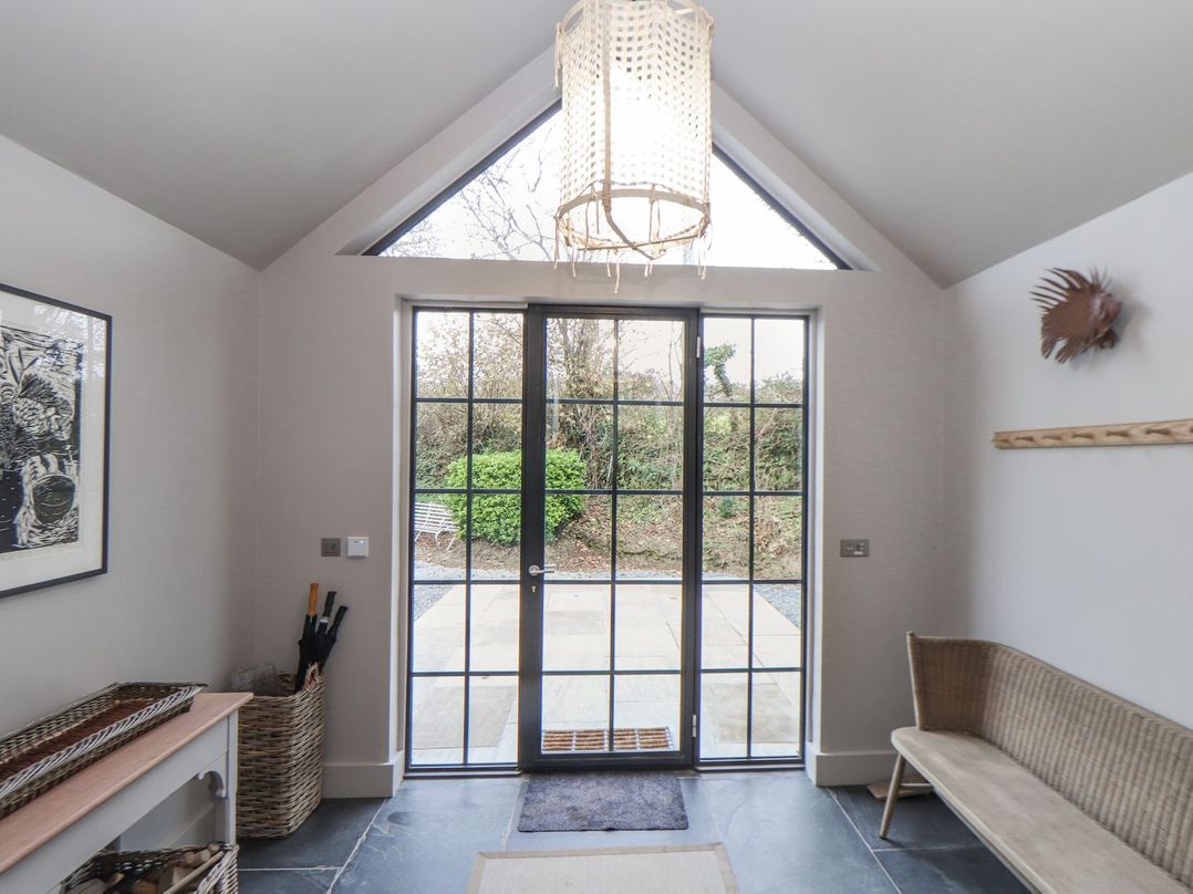 A hallway with a door and bench at Wood Meadow in Helston