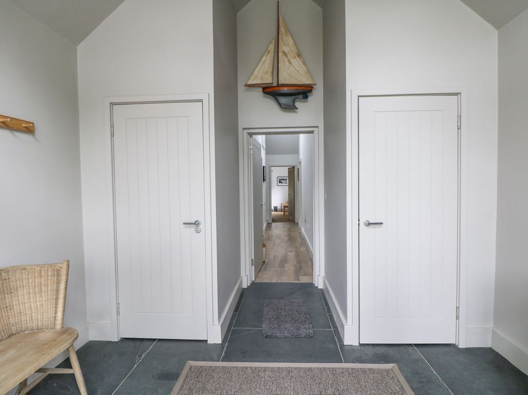 A hallway with two doors and a decorative sailboat at Wood Meadow in Helston