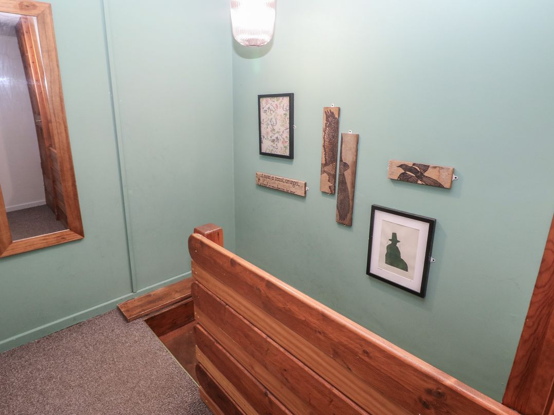 A hallway with wood paneling and framed art at Cabin No. 9 - Salt and Fern Cabins in Goytre near Port Talbot