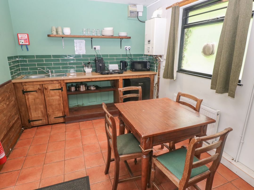A kitchen with cabinets, a table, and appliances at Cabin No. 10 - Salt and Fern Cabins in Goytre near Port Talbot