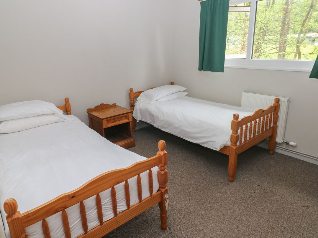 A bedroom with two single beds and a nightstand at Cabin No. 12 - Salt and Fern Cabins in Goytre near Port Talbot