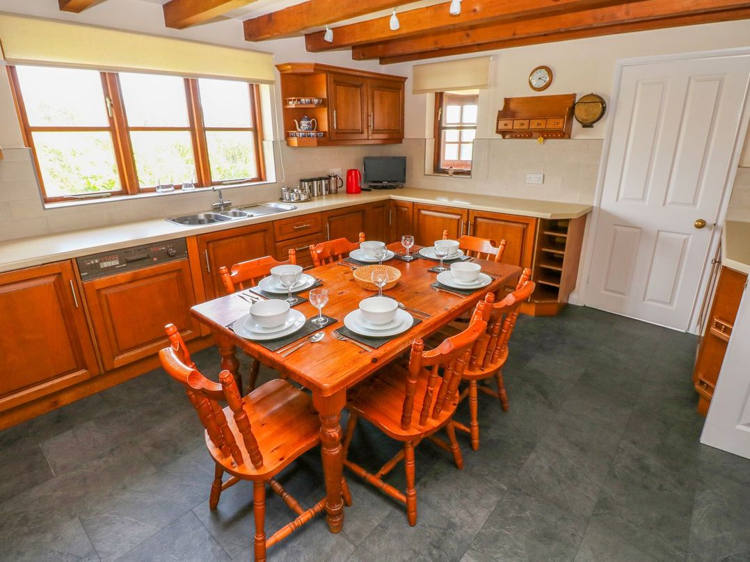 A kitchen with a wooden dining table and chairs at Park Hall Cottage in Solva