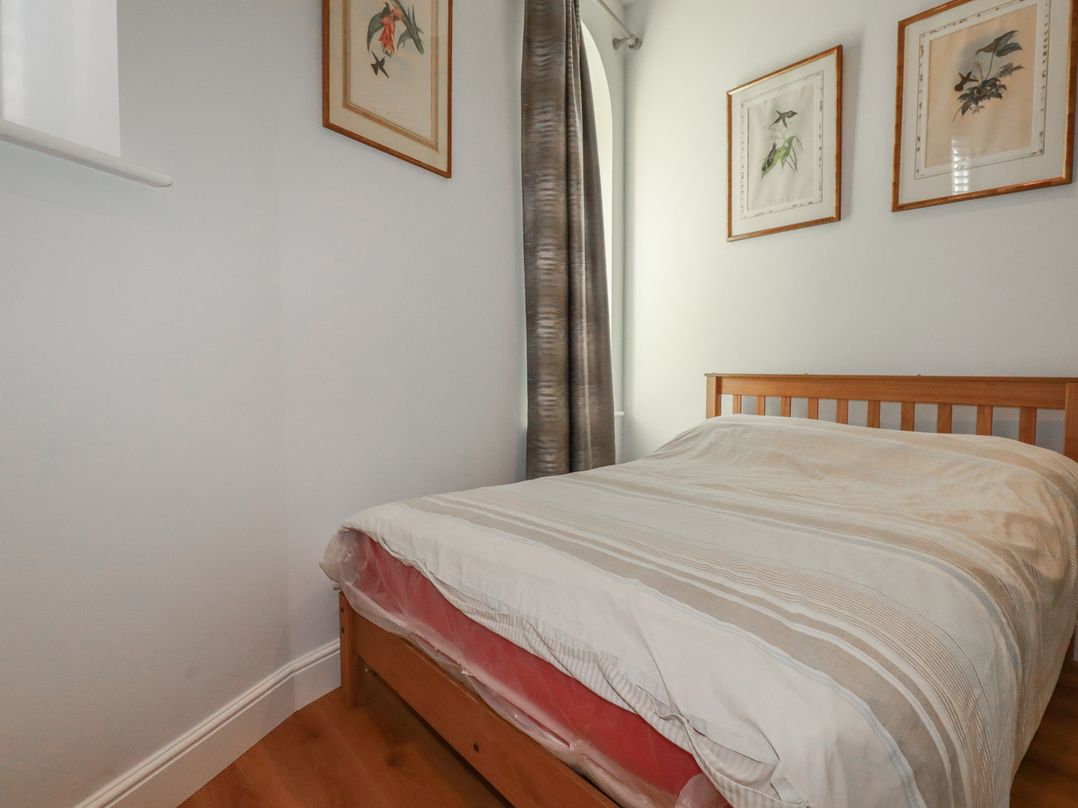 A bedroom with a bed and framed pictures at Farthings, The Old Chapel St Austell