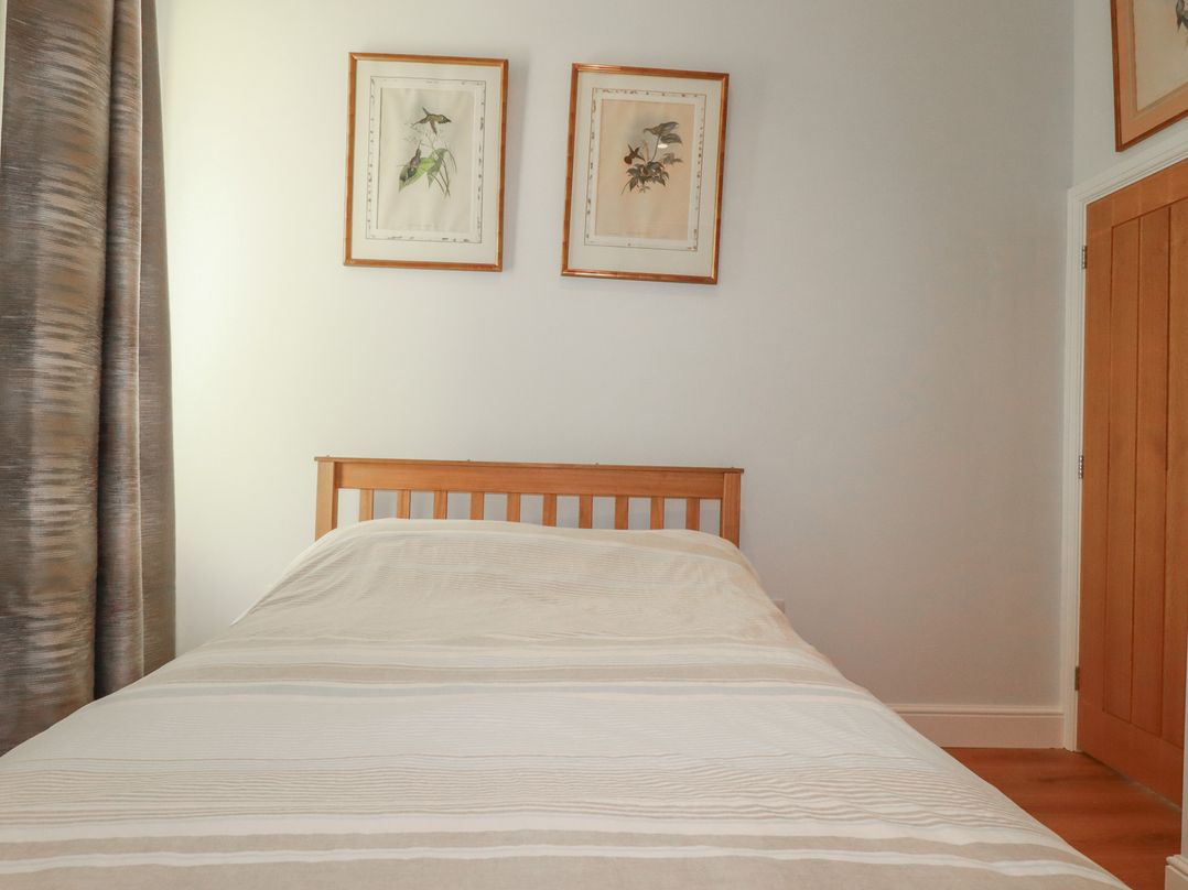 A bedroom with a bed and framed pictures at Farthings, The Old Chapel in St Austell