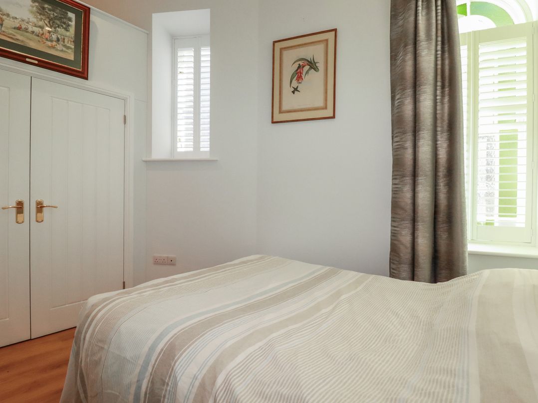 A bedroom with a bed and window at Farthings, The Old Chapel, St Austell