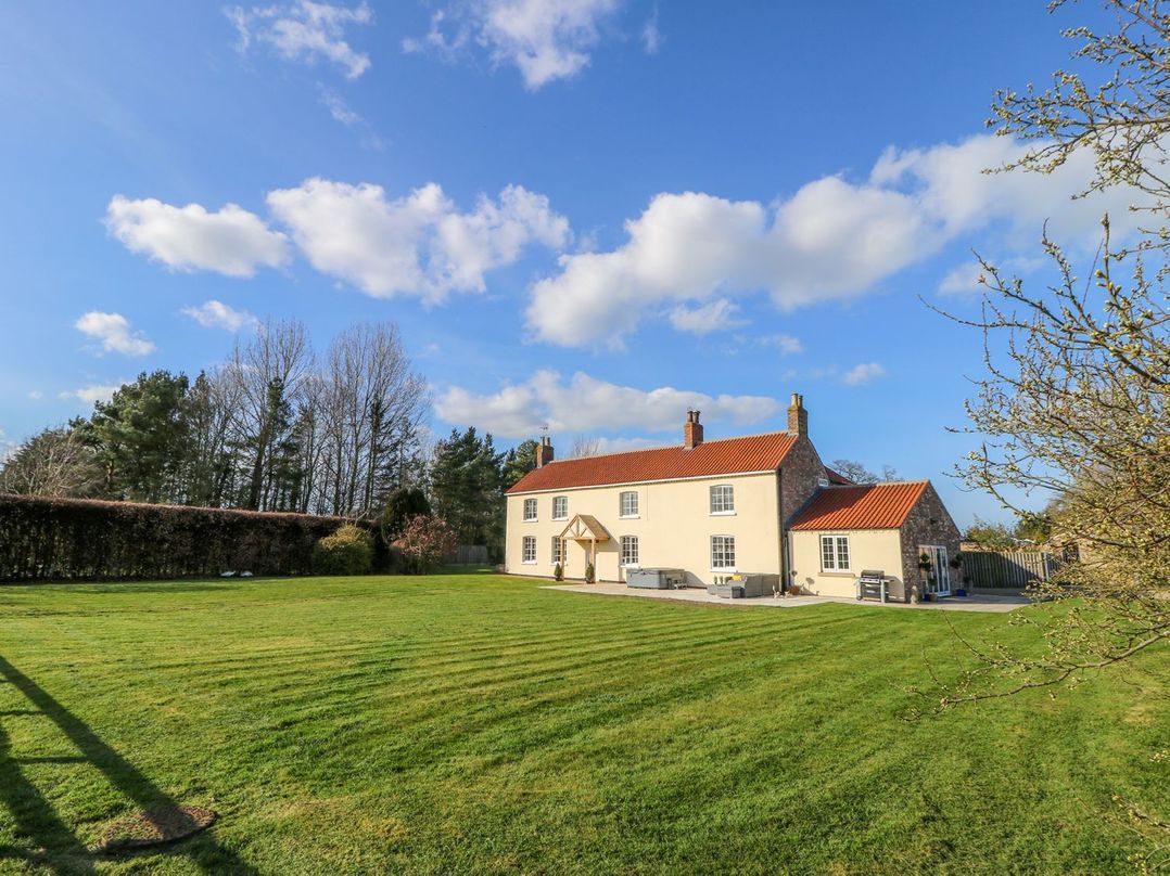 An outdoor view of a house with a lawn at Tuft House in Hovingham