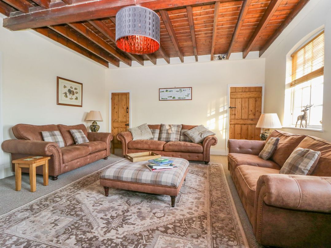 A living room with sofas, a footstool, and a lamp at Tuft House in Hovingham