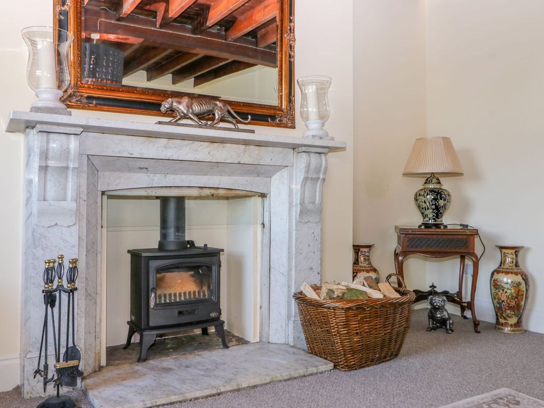 A sitting room with a fireplace and a basket of firewood at Tuft House in Hovingham