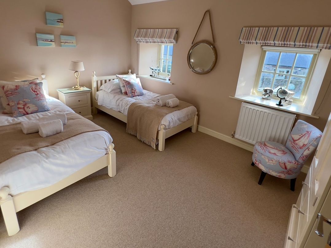 A bedroom with two beds and a bedside table at The Chimney in Bamburgh