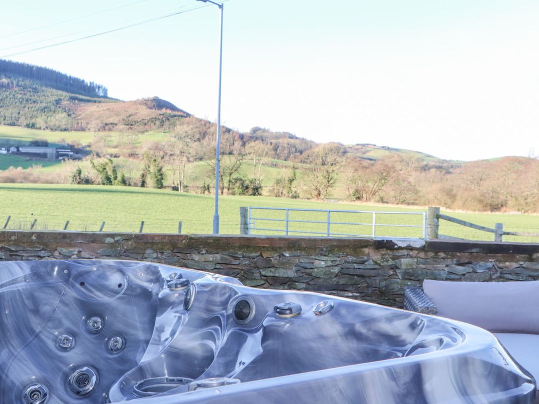 A hot tub with a view of hills and fields at The Steading in Dumfries