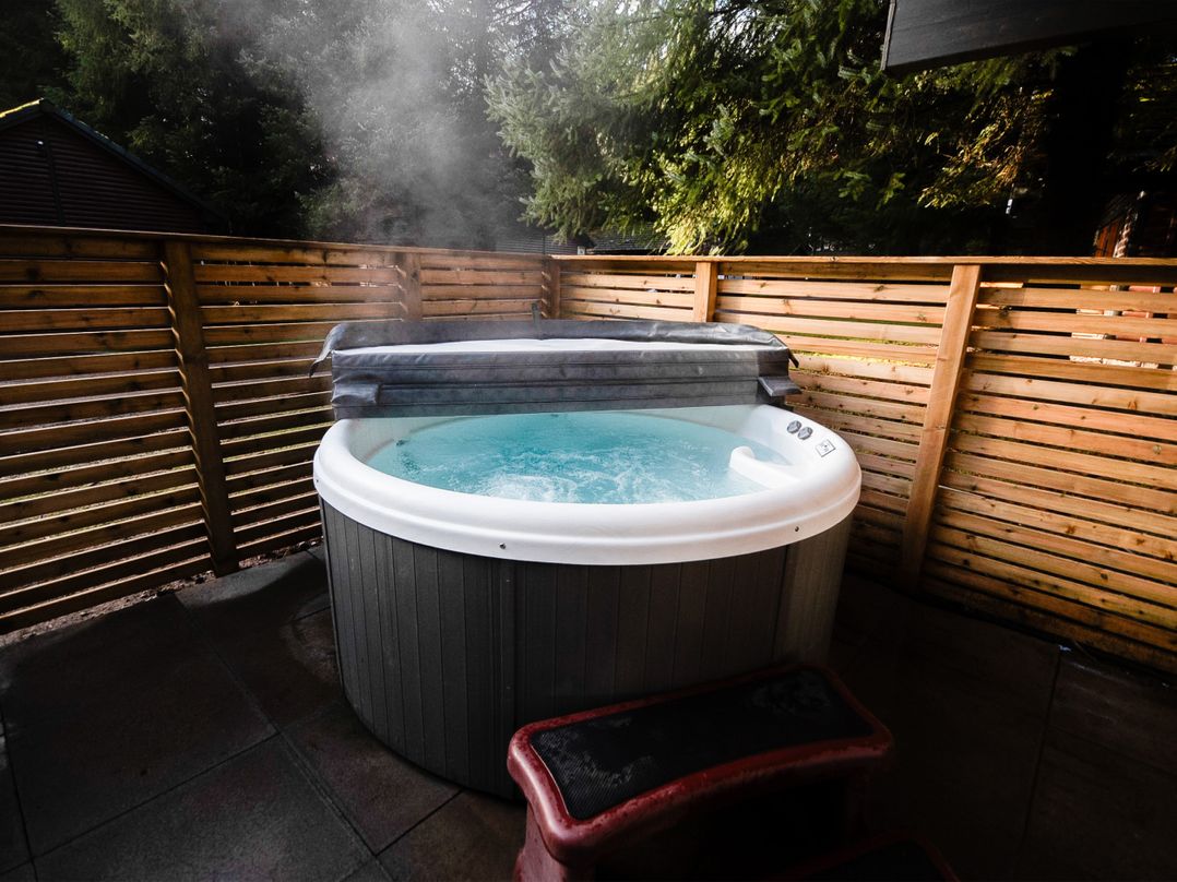 A hot tub with a cover surrounded by a wooden fence at Sidlaw Spa Fowlis near Dundee