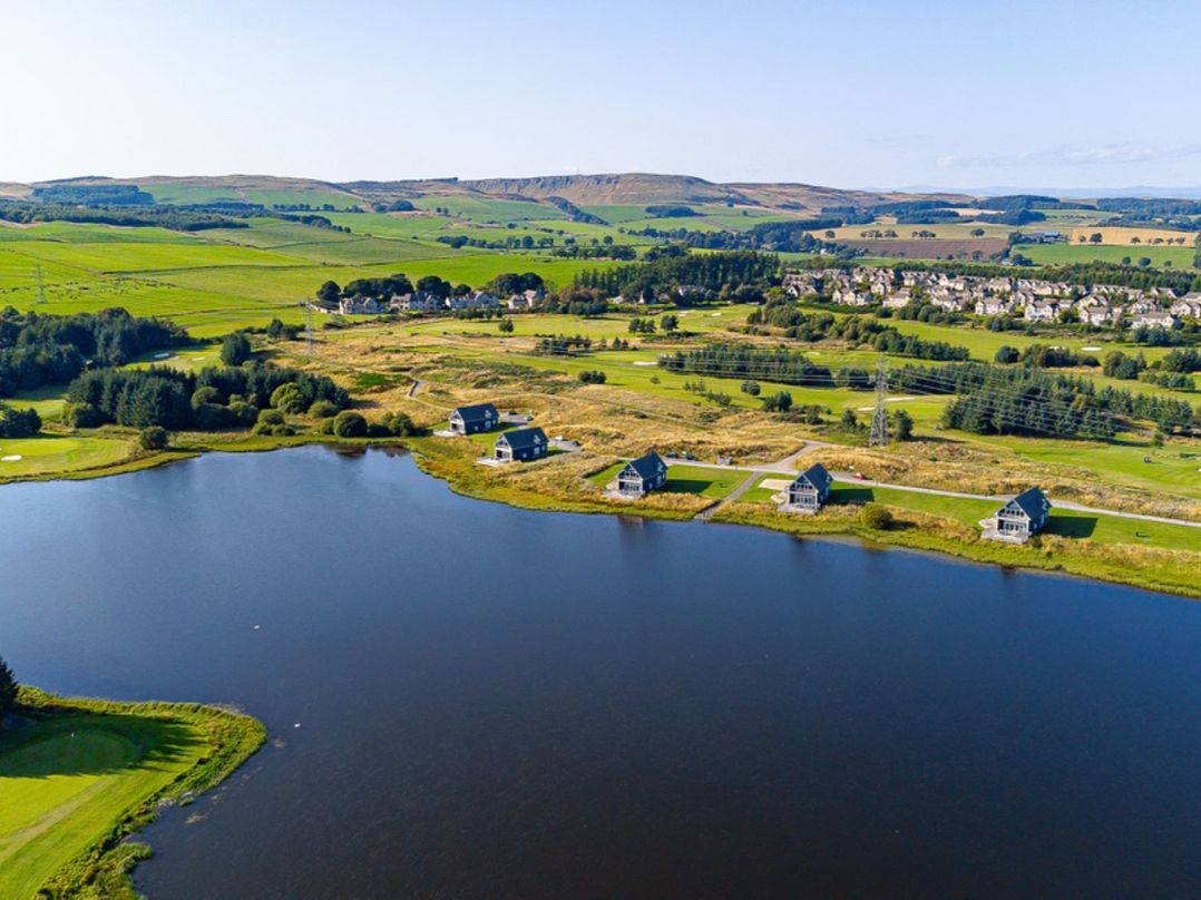 An aerial view of houses by a lake with fields in the background at Sidlaw Spa (Pet) Fowlis near Dundee