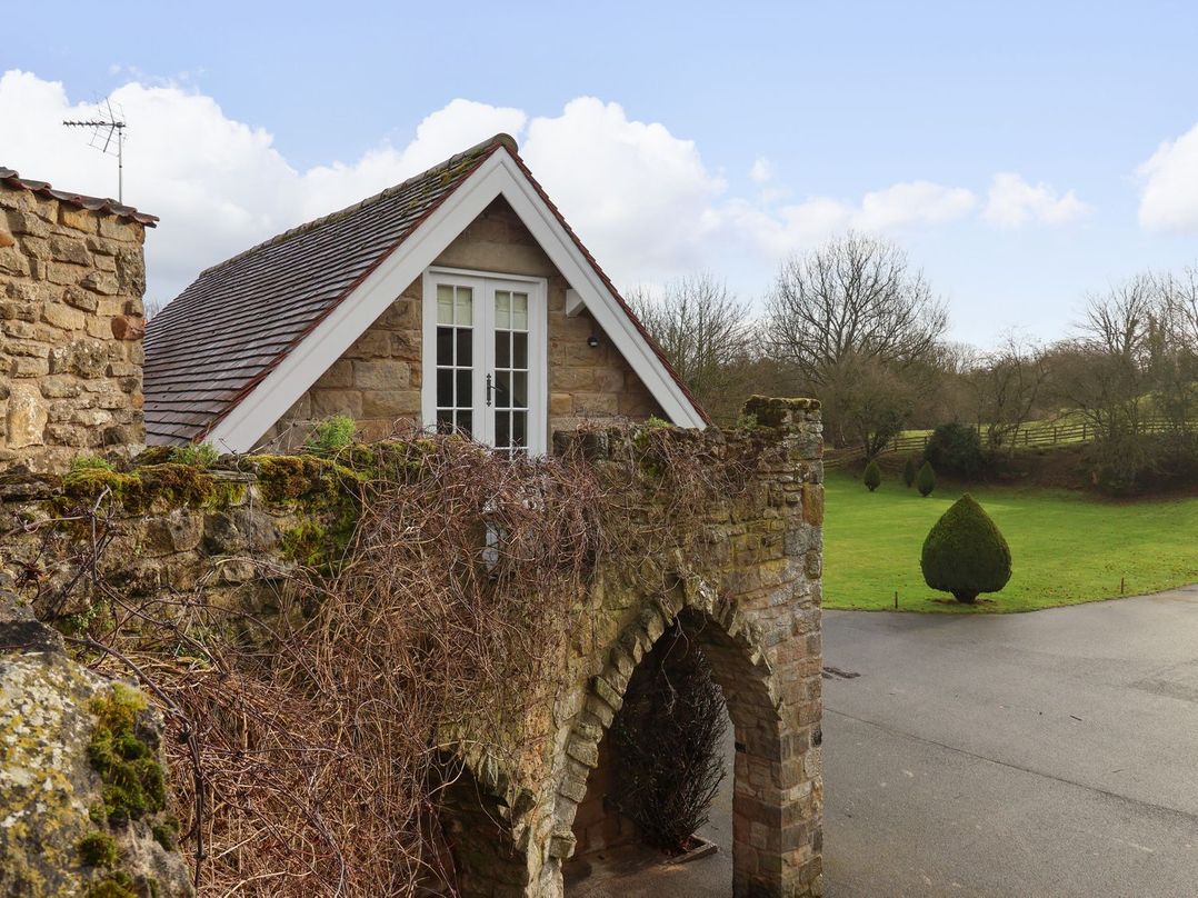 A house with a stone wall and windows in the garden at The Bothy in Knaresborough