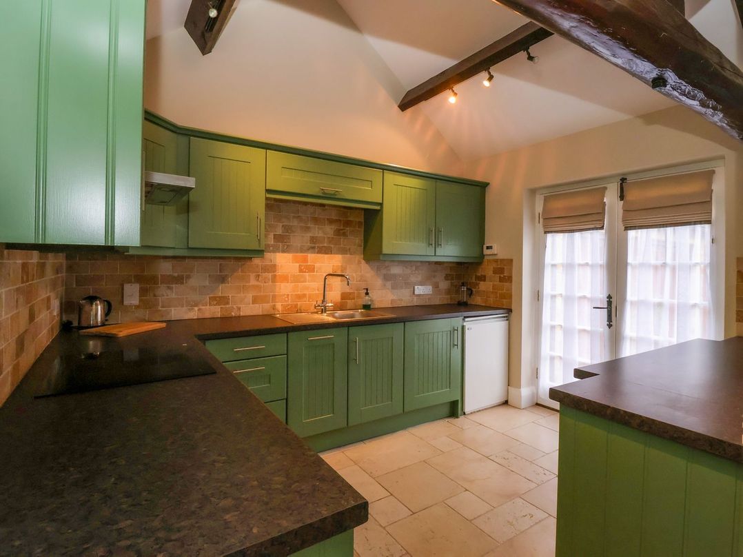 A kitchen with green cabinets and a sliding door at The Bothy in Knaresborough