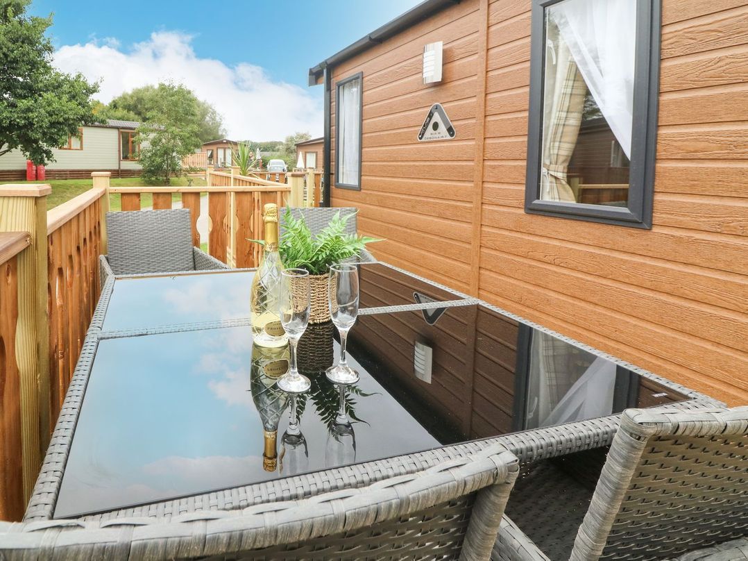 An outdoor seating area with a table and chairs at Hedgehog Lodge in Carnforth