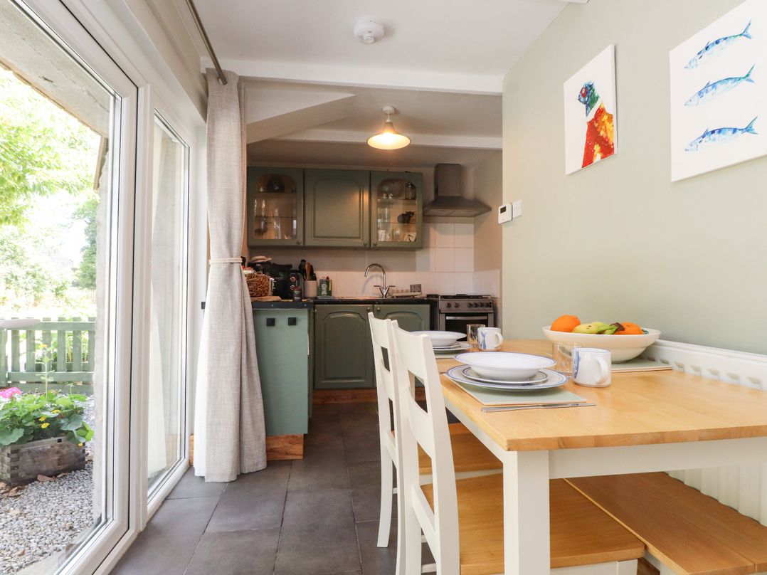 A kitchen with a table and chairs at Woodman's Lodge Llanallgo near Moelfre