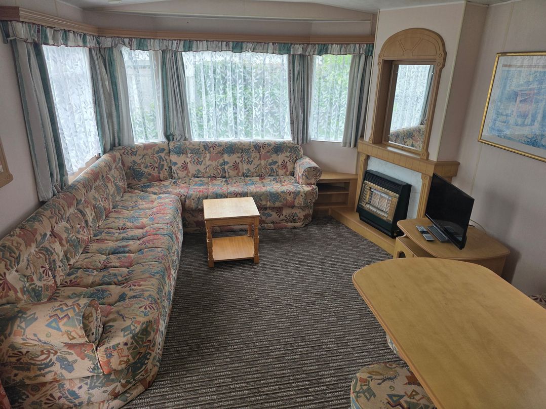 A living room with a sofa, coffee table, and television at Number 186 Owens Caravan Park in Abergele