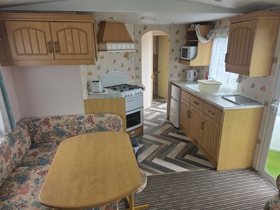 A kitchen with cabinets and appliances at Number 186 Owens Caravan Park, Abergele