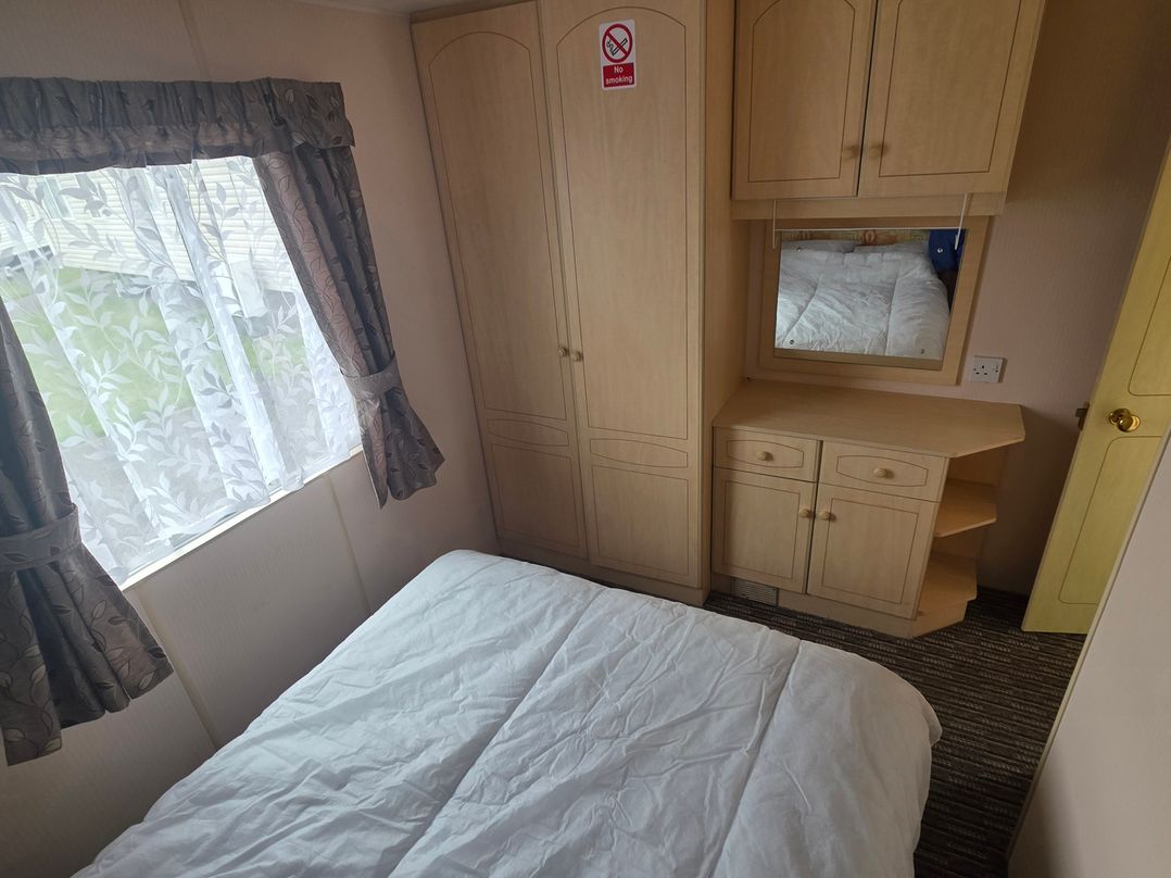 A bedroom with a bed and a wardrobe at Number 186 Owens Caravan Park in Abergele