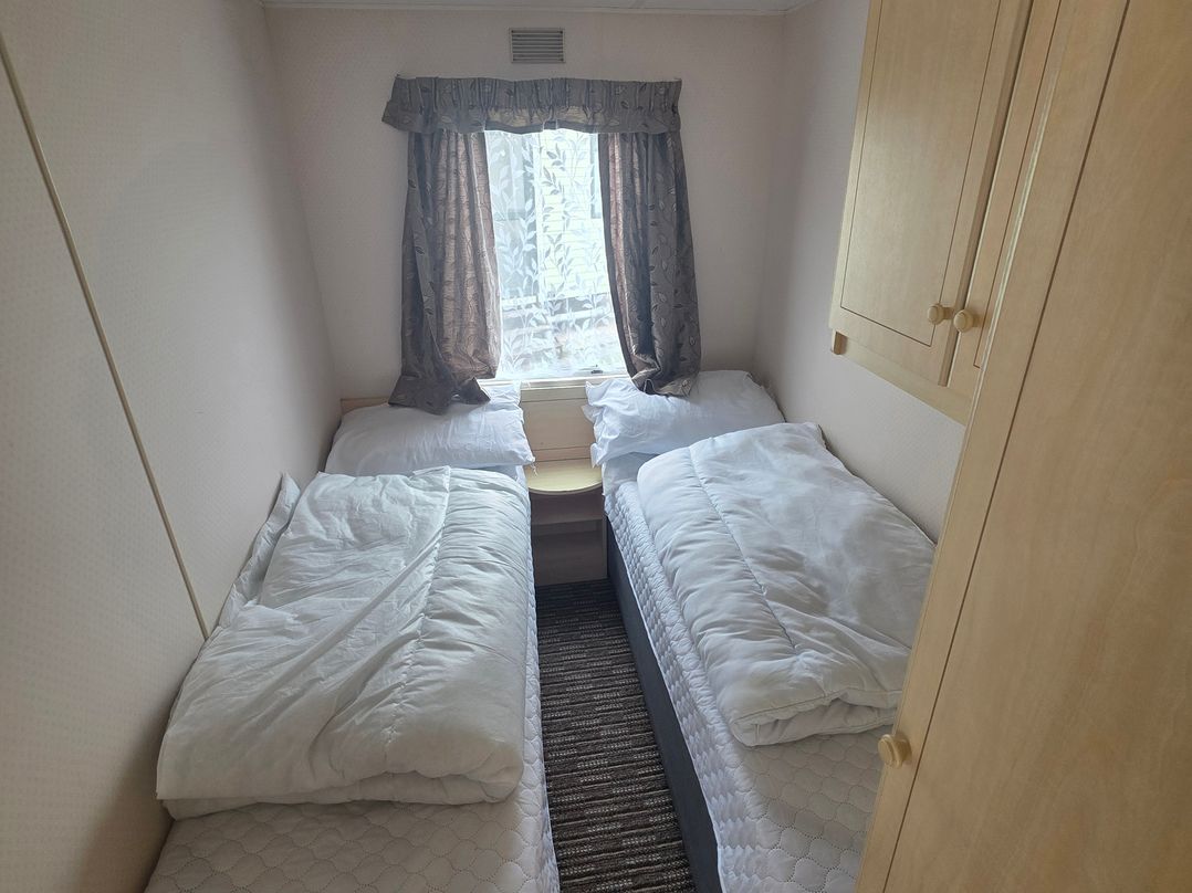 A bedroom with two single beds and a window at Number 186 Owens Caravan Park in Abergele