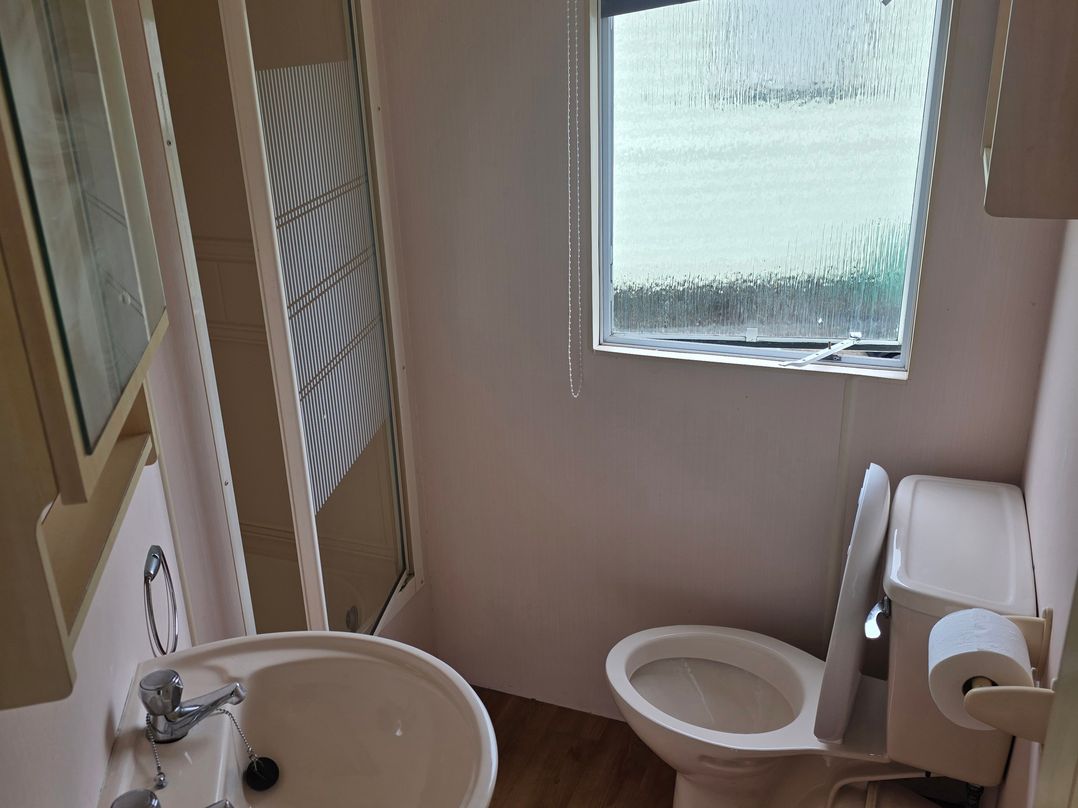 A bathroom with a sink, toilet, and shower at Number 186 Owens Caravan Park Abergele