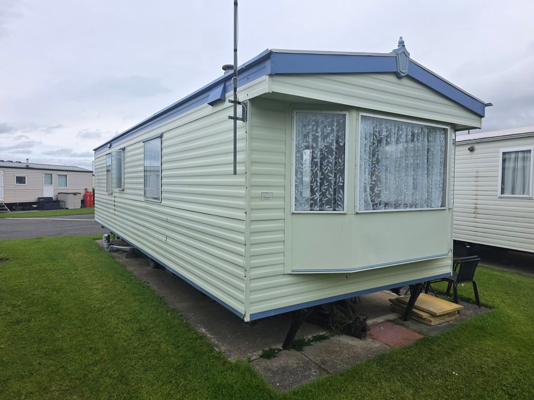 A caravan with windows and grass at Number 186 Owens Caravan Park, Abergele