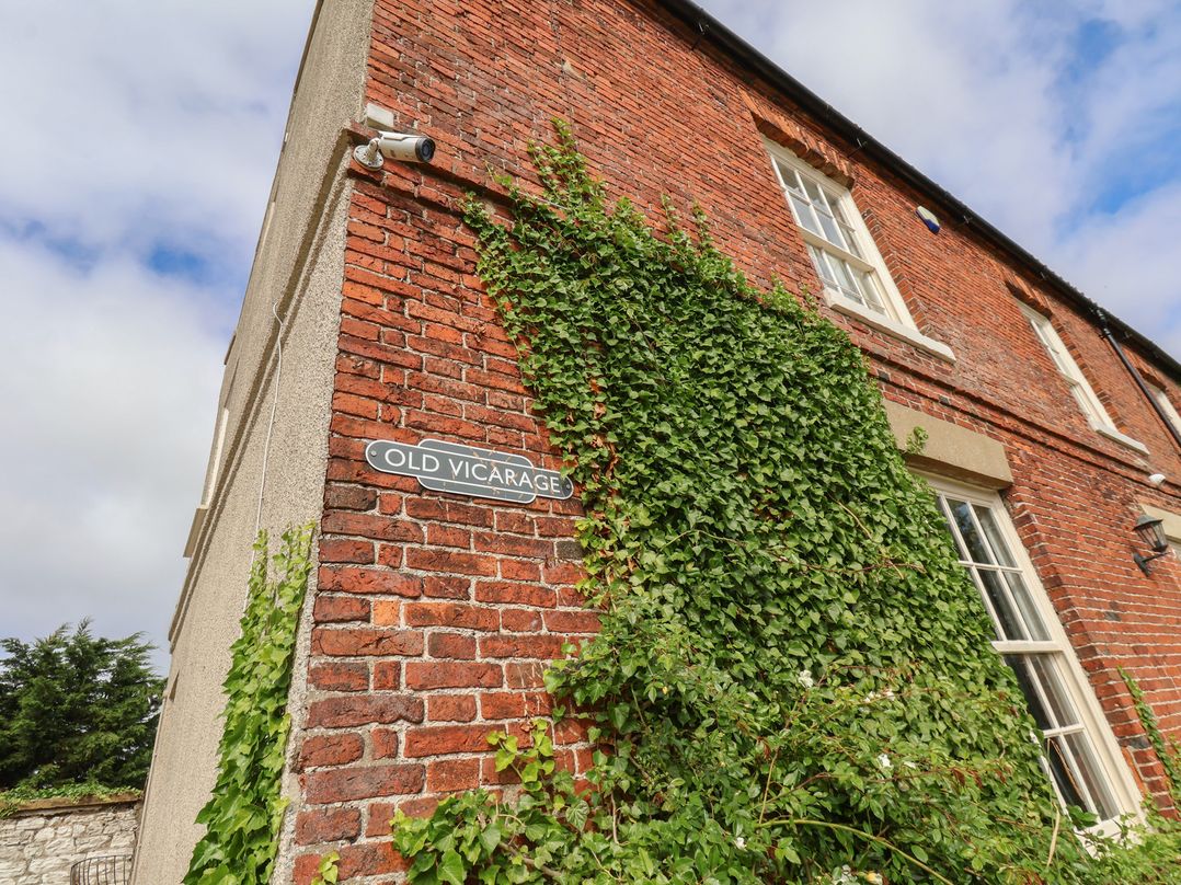 An exterior view of a brick building with ivy and a sign at Old Vicarage in Reighton near Filey