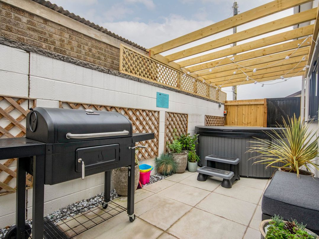 An outdoor space with a barbecue and hot tub at Seagull Shack Morfa Bychan