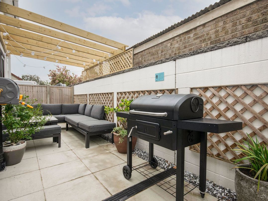 An outdoor patio with a sofa and grill at Seagull Shack Morfa Bychan