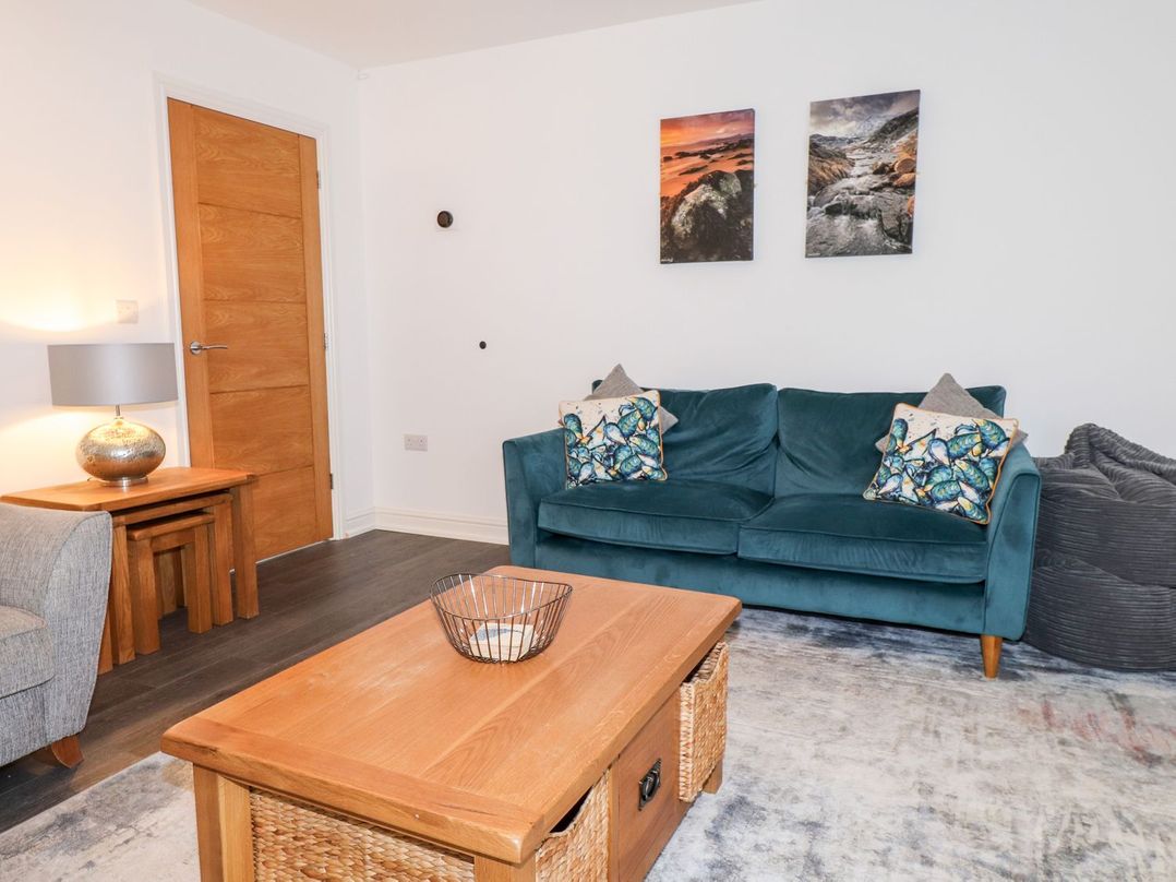 A living room with a green sofa and wooden coffee table at Seagull Shack in Morfa Bychan