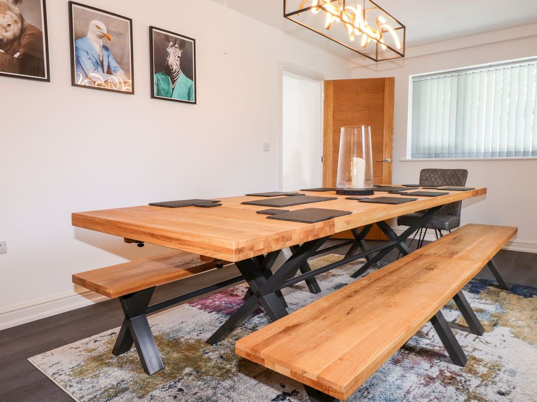 A dining room with a wooden table and benches at Seagull Shack Morfa Bychan