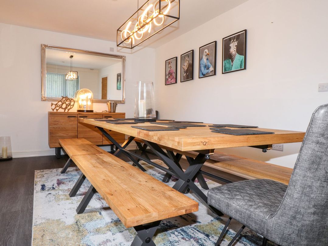 A dining room with a wooden table and chairs at Seagull Shack Morfa Bychan