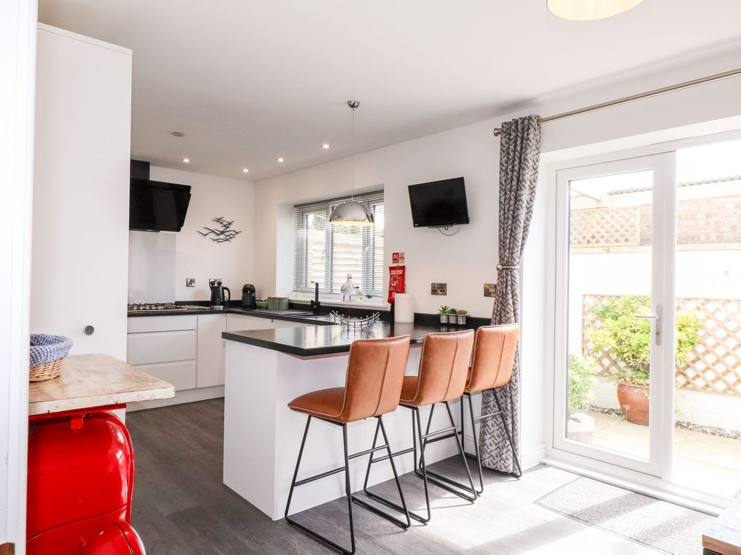 A kitchen with a counter and bar stools at Seagull Shack in Morfa Bychan