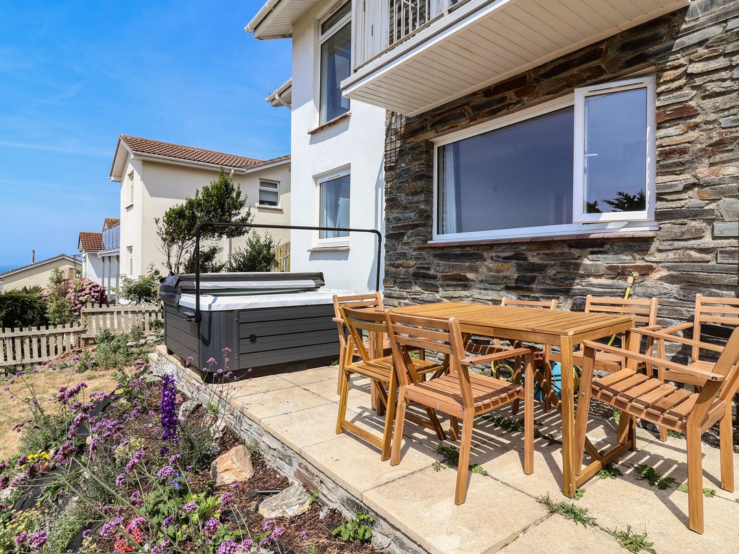 An outdoor area with a hot tub and dining table at Belvedere in Woolacombe