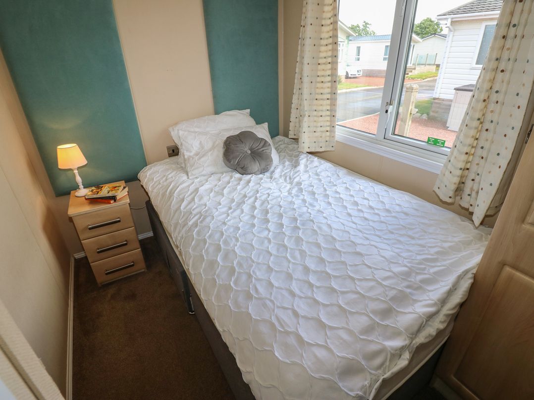 A bedroom with a single bed and bedside lamp at Plot 34 near Armathwaite