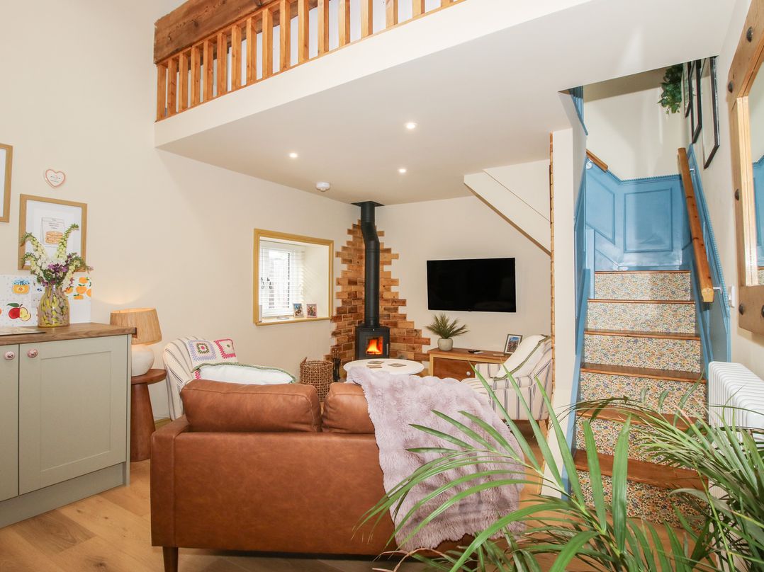 A living room with a fireplace and staircase at The Dinky Dairy in Treflach near Trefonen