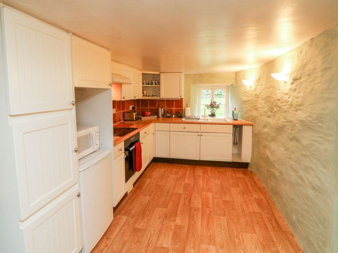A kitchen with cabinetry and appliances at Whitefield Cottage in Barnstaple