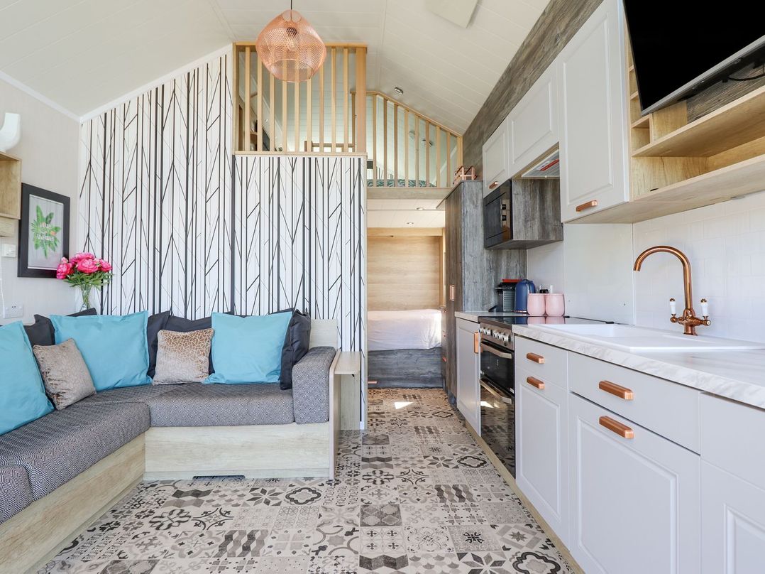 A living room with a sofa and kitchen area at Posh Pod Cemaes Bay