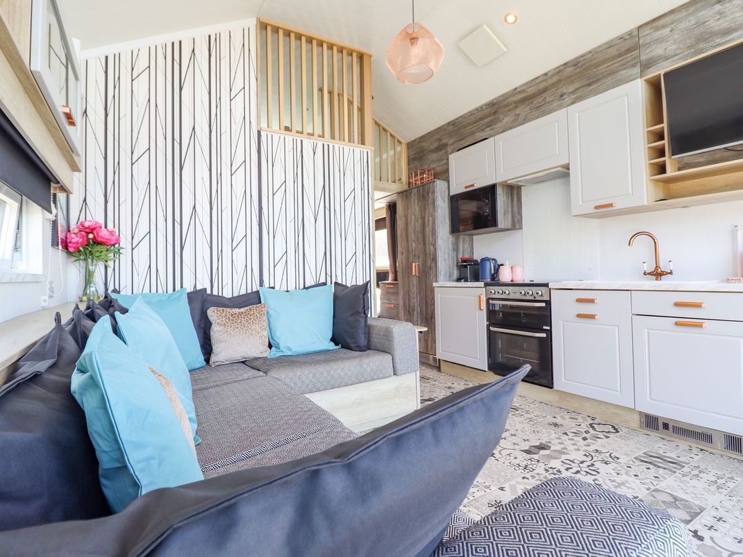 A living room with a couch and kitchen area at Posh Pod in Cemaes Bay