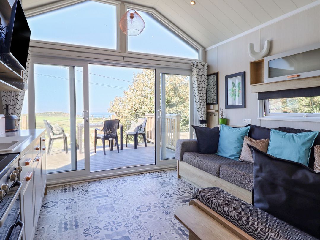 A living room with a sofa and sliding glass door at Posh Pod in Cemaes Bay