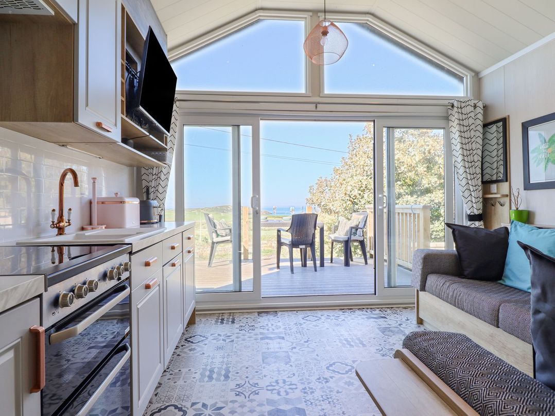 A kitchen with a glass door and seating area at Posh Pod in Cemaes Bay
