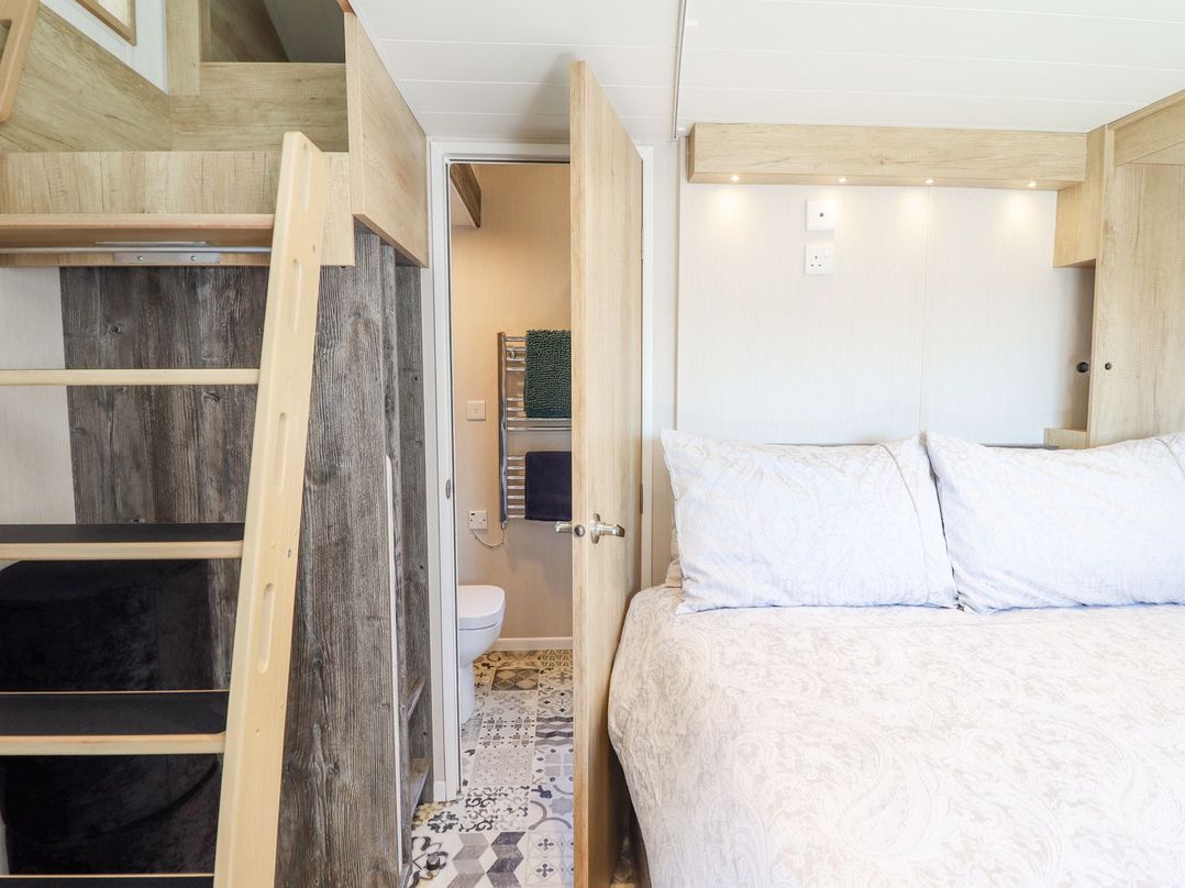 A bedroom with a bed and a bathroom door at Posh Pod in Cemaes Bay