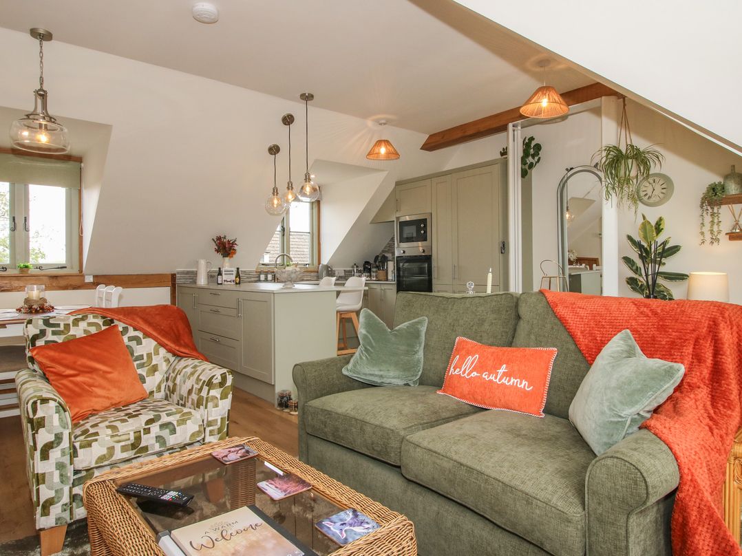 A living room with a sofa and kitchen area at Little Acre in Leominster