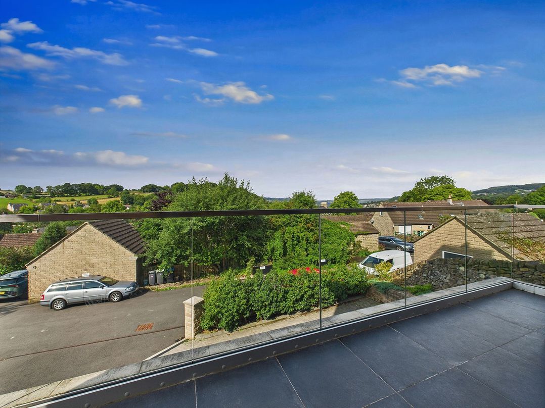 A view from a balcony overlooking houses and greenery at Oakwood House Tansley near Matlock