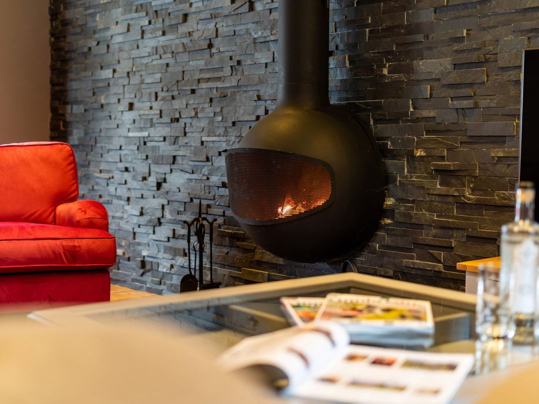 A living room with a fireplace and a red sofa at Prospect House Windermere