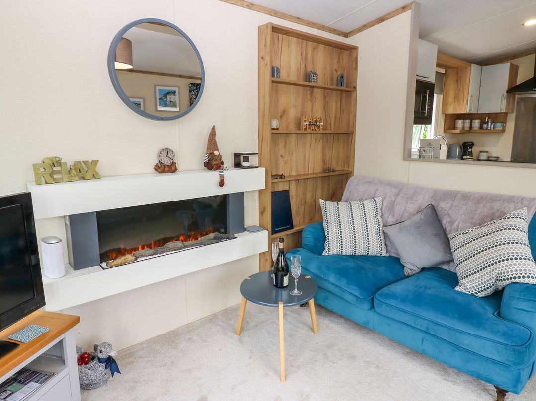 A living room with a blue sofa and a fireplace at Plot 41 High Hesket near Armathwaite