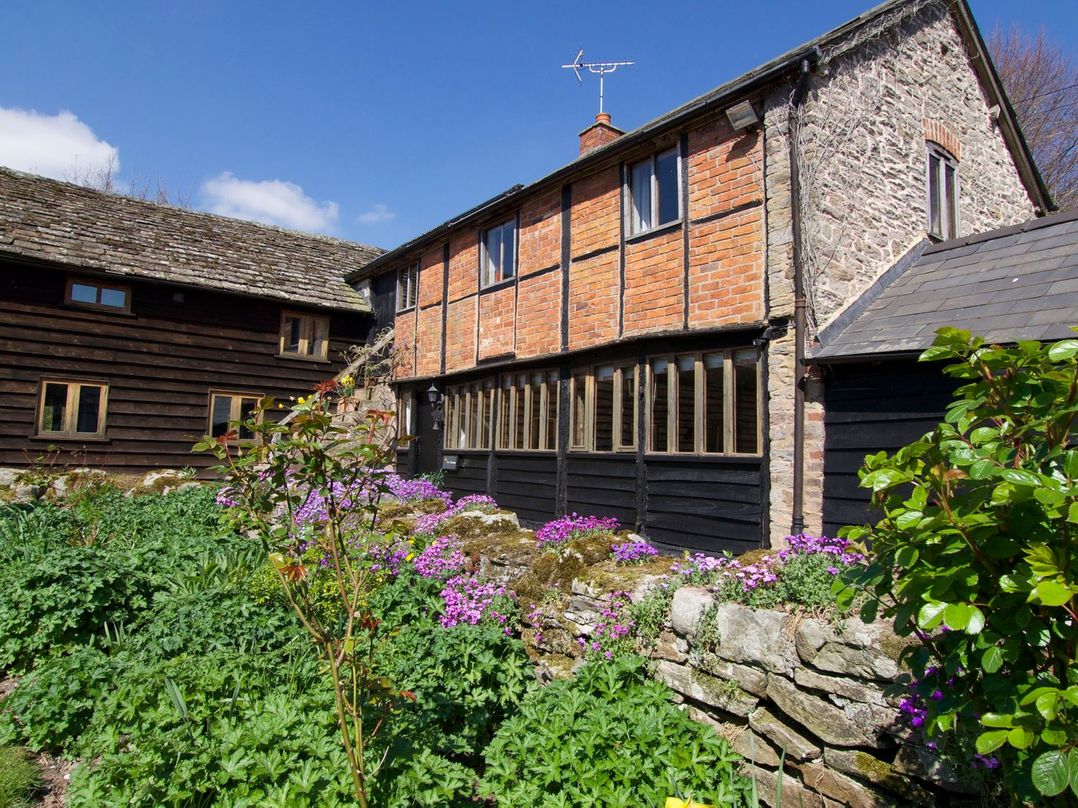 The exterior of a building with windows and flowers at The Old Barn in Hereford